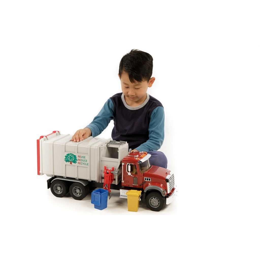 Red Bruder Mack Granite garbage truck toy with gray side-loading container and blue yellow recycling bins